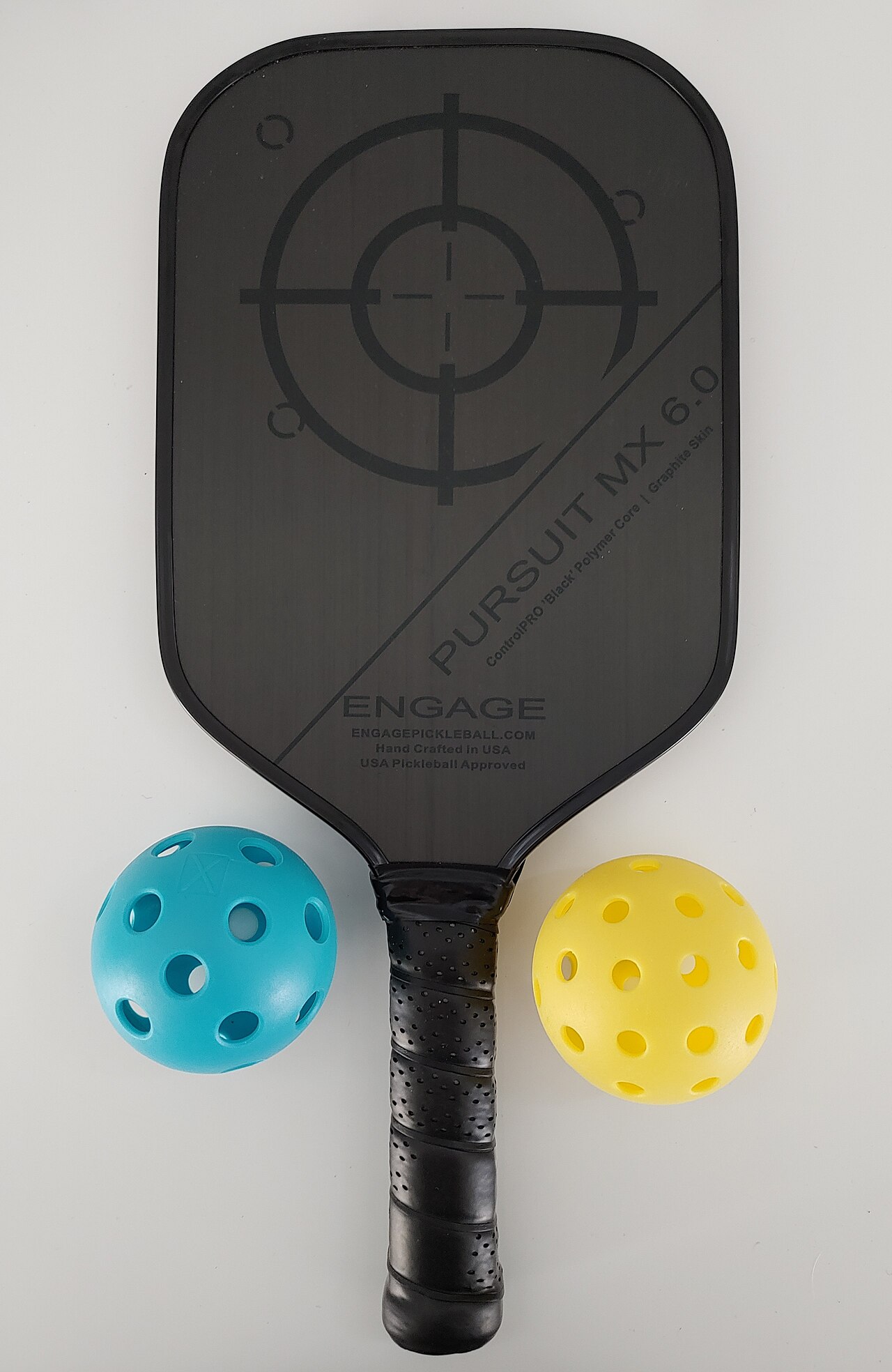 A pickleball paddle resting with two pickleballs